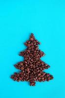 Christmas tree made from coffee beans on a blue background, top view. photo