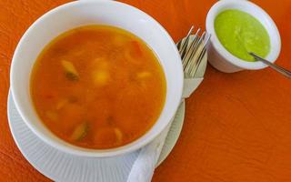 Vegetable soup with carrots greens onions tomato in white bowl. photo