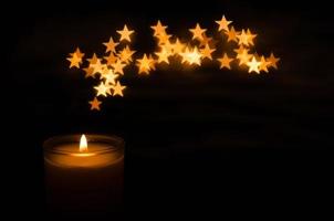 Aromatic candle with flame and star shape bokeh on dark background for Thanks giving and Christmas day. photo