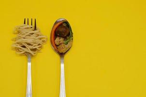 comida vegana: fideos salteados con champiñones shiitake, zanahoria, tofu y vegetales para el festival de nueve dioses emperadores o festival vegetariano en tailandia poniendo tenedor y cuchara con fondo amarillo. foto