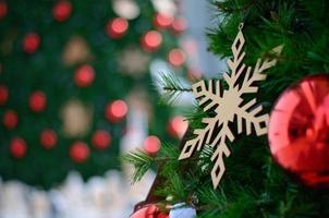 Red bauble and other ornament hanging on Christmas tree with bokeh background from another Christmas tree photo