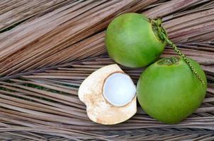 cocos jóvenes frescos de tailandia y cortados por la mitad con carne jugosa y dulce de color blanco que es fresca para el verano aislada en el fondo de hojas marrones secas foto