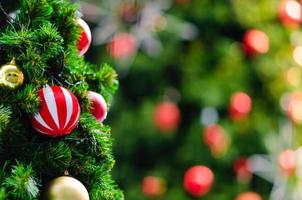 Colorful baubles hanging on Christmas tree with bokeh background from another bigger Christmas tree. photo