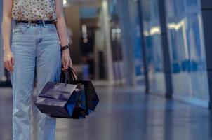 Woman holding shopping bags with shopping mall background. Black Friday sale concept. photo