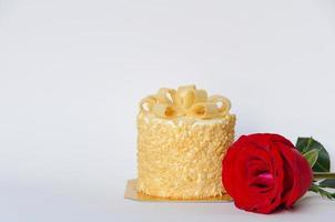 el pastel de mantequilla y la rosa de color rojo fresco que dan como regalo de cumpleaños aislado en fondo blanco foto