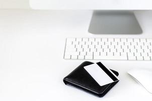 enfoque selectivo en billetera negra y tarjeta de crédito con teclado inalámbrico, mouse y pantalla de computadora para compras en línea y concepto de lunes cibernético. foto