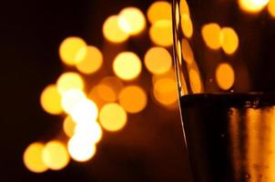 A glass of wine has the shadow of yellow and orange bokeh light on it which isolated on dark color background photo