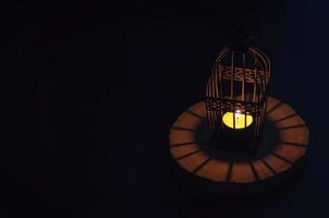 Beautiful Lantern that have moon symbol on top that have light from candle shining on wooden tray with dark background. photo