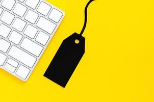 etiqueta de precio negra con teclado inalámbrico para compras en línea sobre fondo amarillo. concepto de lunes cibernético y lunes negro. foto