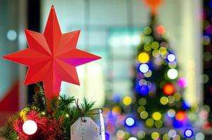 Star ornament puts on top of Christmas tree for Holiday decoration with colorful lights on background. photo