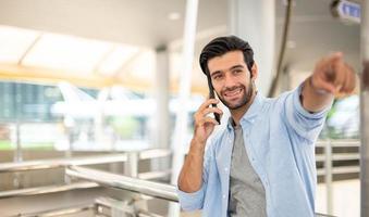 Businessman pointing to something while using a smartphone to talk with his friend at the outdoor photo