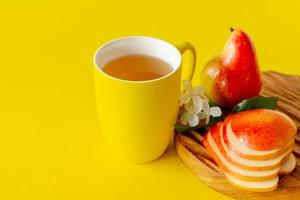 Cup of pear juice and ripe pears on wooden cutting board and yellow background with copy space. photo