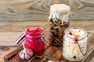 Sauerkraut variety preserving jars. Homemade Sauerkraut with Carrot and Salad Cabbage with Beetroot on a wooden table. Fermented food. photo