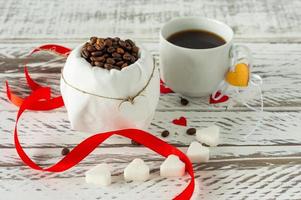 Festive St Valentines composition. Black romatic coffee with sugar in heart sashape and red scattered paper heart confetti photo