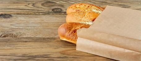 arranged french baguettes in paper bag and wheat on rustic wooden tabletop photo
