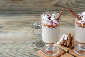 bebida caliente de cacao o chocolate con malvavisco en una taza de vidrio sobre una mesa de madera. concepto de vacaciones acogedoras de navidad y año nuevo, espacio de copia foto