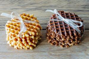 Two piles of delicious belgian waffles with honey and chocolate on wooden table photo