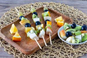 canapés de frutas para un buffet en un plato. mezcla de mandarina, manzana, kiwi, uva, plátano. foto