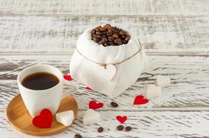 Festive St Valentines composition. Black romatic coffee with sugar in heart sashape and red scattered paper heart confetti photo