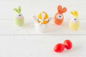 arreglo decoración feliz pascua concepto de fondo de vacaciones. huevos pintados de pascua con huevos tejidos a mano sobre mesa de madera blanca. colores pastel foto