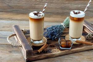 taza de café con leche con jarabe de lavanda casero y flores en una bandeja de madera. desayuno acogedor. foto