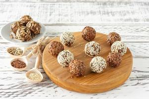 Healthy raw energy balls. Candy vegan balls of dates, coconut pulp, nuts on a wooden desk. Concept of useful homemade no sugar candies photo