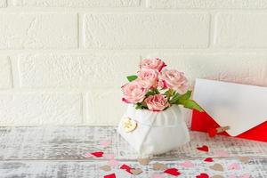 arreglo festivo de ramo de rosas rosadas y sobre con carta de saludo para vacaciones foto