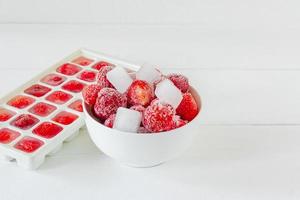 Fresh ripe strawberries frozen in ice cubes on white background. Healthy summer eating. photo