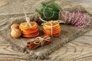 Christmas composition. Arrangement of dry Oranges, cinnamon sticks, fur tree branches and walnuts on wooden background. Rustic, Holiday spices ingredients photo