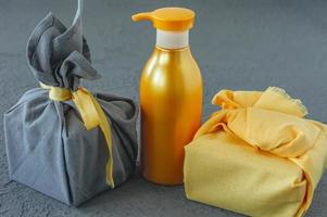 tratamiento de spa y concepto de cuidado corporal en colores del año 2021: amarillo iluminador y gris definitivo. presente envuelto en estilo furoshiki. foto