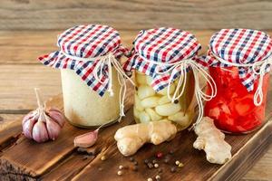 Homemade tomatoes preserves in glass jars in white wicker basket on wooden background photo