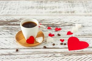 Festive St Valentines composition. Black romatic coffee with sugar in heart sashape and red scattered paper heart confetti photo