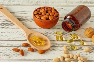 Fish oil capsules and assortment of nuts on wooden background and texture, vitamin D, omega supplement, selective focus. photo