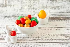 Easter spring composition with painted eggs, ceramics bunny and han on wooden table. Festive decoration for Easter holidays photo