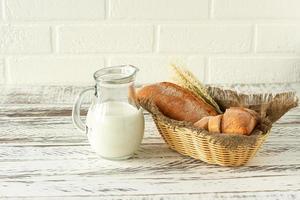 Composition of various baked products in basket on rustic background with jug of milk. Homemade fresh pastry. photo