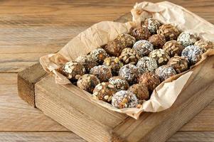 Vegan healthy energy balls with oatmeal, chia seed, coconut flakes, cocoa, dried fruits and almond. No cook energy bites in white wooden box. photo