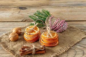 Christmas composition. Arrangement of dry Oranges, cinnamon sticks, fur tree branches and walnuts on wooden background. Rustic, Holiday spices ingredients photo