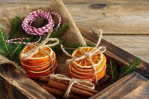 Rustic christmas composition with dried oranges, cinnamon sticks and fir tree branches in a wooden box photo
