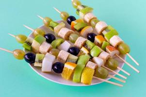 conjunto de canapés con frutas, bayas en plato blanco sobre fondo azul foto