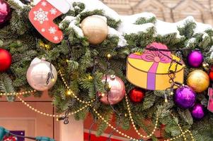 cerca de la decoración festiva de la ciudad navideña. brunch fure tree cubierto de nieve decorado con adornos y guirnaldas foto