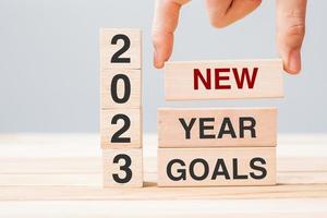 hand holding wooden block with text 2023 NEW YEAR NEW GOALS on table background. Resolution, strategy, solution, business and holiday concepts photo