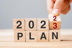 hand flipping block 2022 to 2023 PLAN text on table. Resolution, strategy, goal, motivation, reboot, business and New Year holiday concepts photo