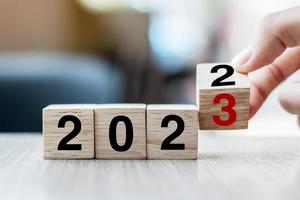 hand flipping block 2022 to 2023 text on table. Resolution, strategy, plan, goal, motivation, reboot, business and New Year holiday concepts photo