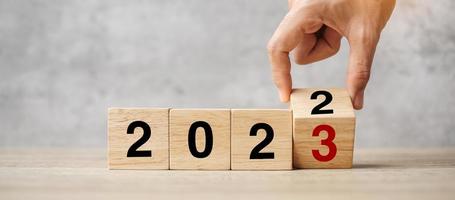 hand flipping block 2022 to 2023 text on table. Resolution, strategy, plan, goal, motivation, reboot, business and New Year holiday concepts photo