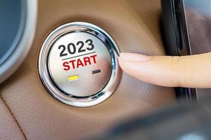 presione con el dedo el botón de encendido de un automóvil con el texto de inicio 2023 dentro del automóvil. año nuevo nuevo tú, pronóstico, resolución, motivación, cambio, objetivo, visión, innovación y concepto de planificación foto