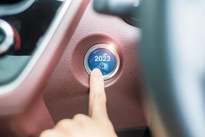 presione con el dedo el botón de encendido de un automóvil con el texto de inicio 2023 dentro del automóvil. año nuevo nuevo tú, pronóstico, resolución, motivación, cambio, objetivo, visión, innovación y concepto de planificación foto