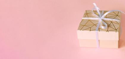 gift box with white ribbon on pink background.