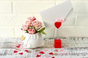 arreglo festivo de ramo de rosas rosadas y sobre con carta de saludo para vacaciones foto