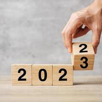 hand flipping block 2022 to 2023 text on table. Resolution, strategy, plan, goal, motivation, reboot, business and New Year holiday concepts photo
