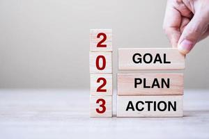 hand holding wooden block with text 2023 GOAL, PLAN and ACTION on table background. Resolution, strategy, solution, goal, business and New Year holiday concepts photo